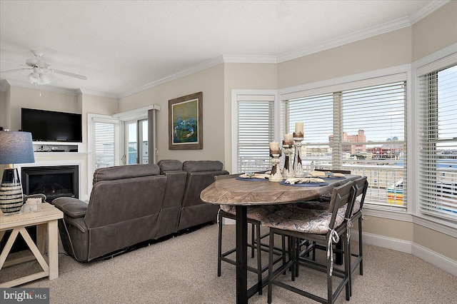 dining room with baseboards, light colored carpet, crown molding, and a fireplace