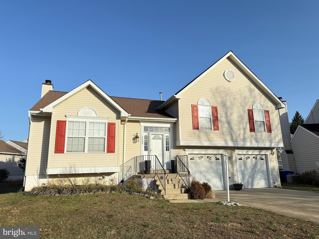 split level home with a front yard, concrete driveway, and an attached garage