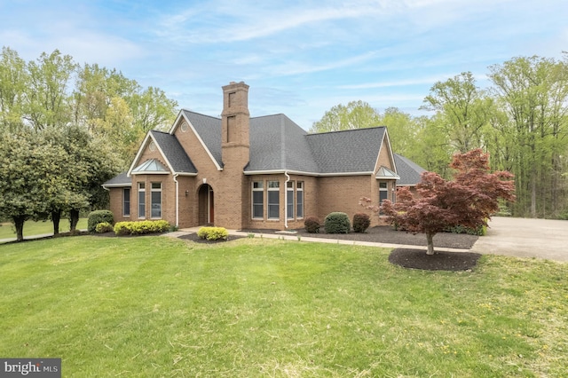 view of front of home featuring roof with shingles, a front lawn, a chimney, and brick siding