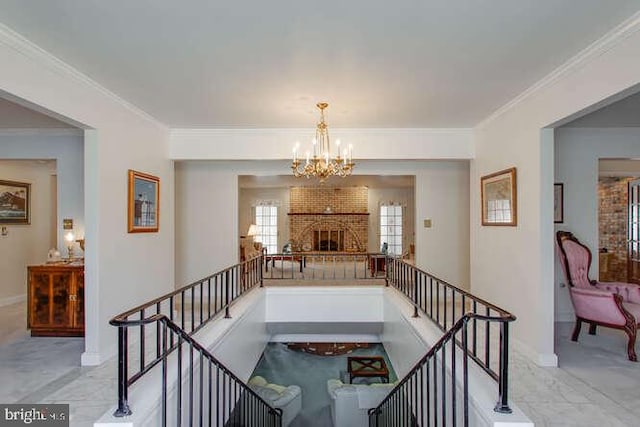 stairway with baseboards, ornamental molding, a brick fireplace, and a notable chandelier