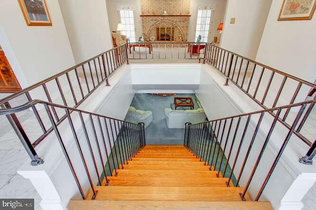 stairway featuring a towering ceiling, a fireplace, and wood finished floors