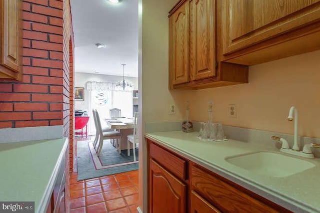 kitchen featuring brown cabinets, light tile patterned floors, light countertops, and a sink