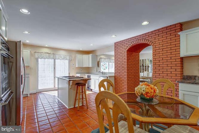 dining room with brick wall, recessed lighting, and light tile patterned flooring