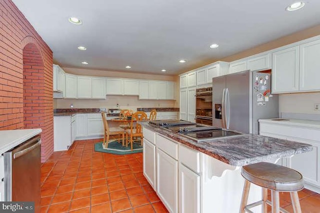 kitchen featuring light tile patterned flooring, recessed lighting, white cabinetry, a center island, and black appliances