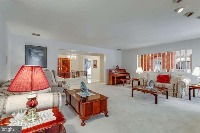 living area featuring carpet, visible vents, and a notable chandelier