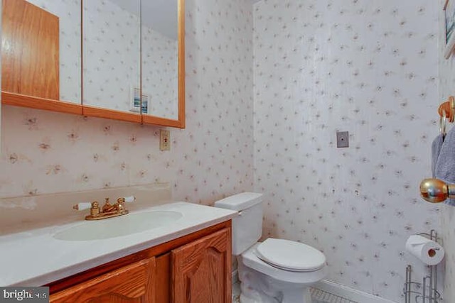 bathroom featuring vanity, toilet, and wallpapered walls