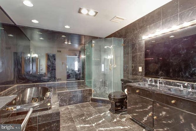 full bathroom with tile walls, double vanity, toilet, a shower stall, and a bath