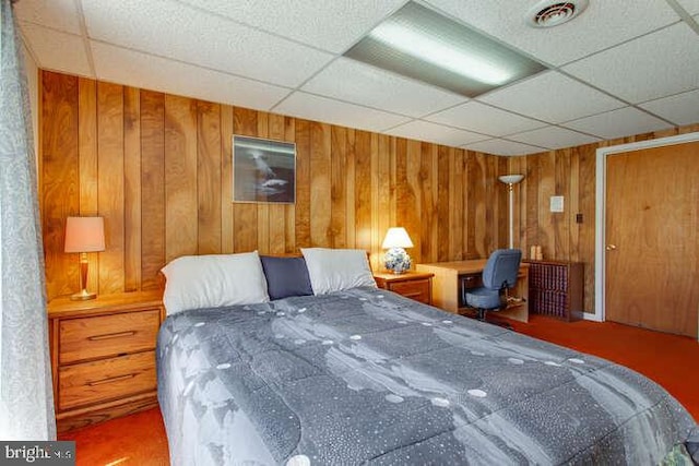 bedroom featuring wood walls, a drop ceiling, built in study area, and visible vents