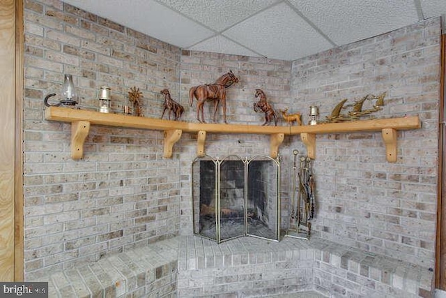 room details featuring a brick fireplace and a paneled ceiling