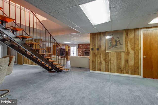 below grade area with stairway, a paneled ceiling, and wooden walls