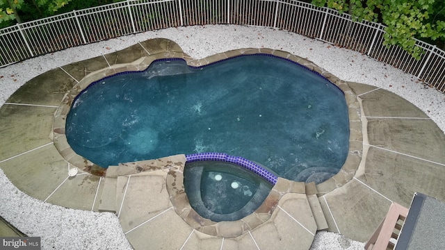 view of pool with a fenced backyard and a pool with connected hot tub