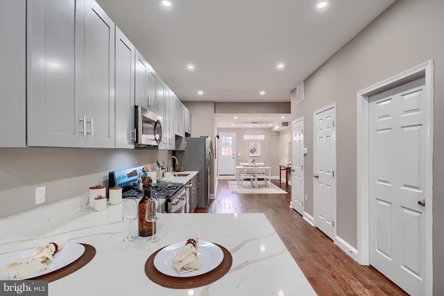 kitchen featuring light stone countertops, appliances with stainless steel finishes, dark wood-style flooring, and recessed lighting