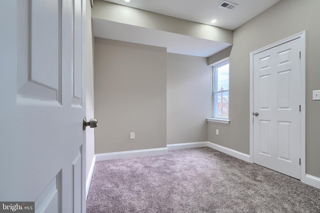 carpeted spare room featuring baseboards and visible vents