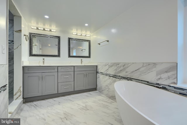 full bathroom featuring double vanity, marble finish floor, a freestanding tub, and a sink