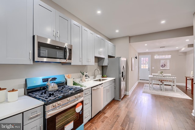 kitchen featuring appliances with stainless steel finishes, light wood-type flooring, light countertops, and a sink