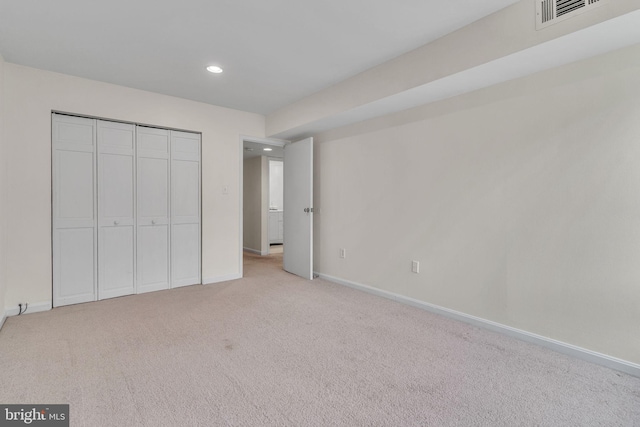 unfurnished bedroom featuring recessed lighting, light carpet, visible vents, baseboards, and a closet