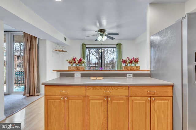 kitchen featuring visible vents, ceiling fan, brown cabinets, light countertops, and light wood-type flooring