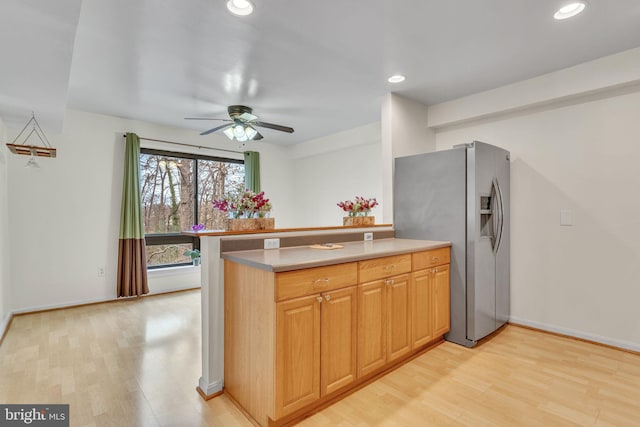 kitchen with stainless steel refrigerator with ice dispenser, recessed lighting, light countertops, light wood-style flooring, and a peninsula