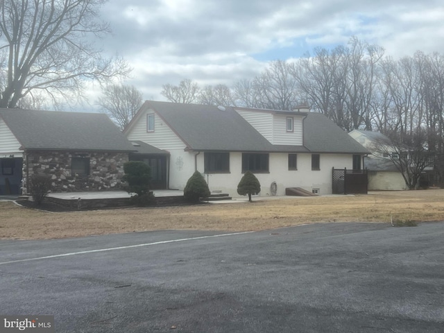 view of front of property with uncovered parking and roof with shingles