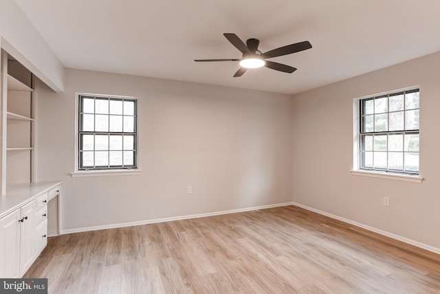 spare room with light wood-style floors, a healthy amount of sunlight, and baseboards