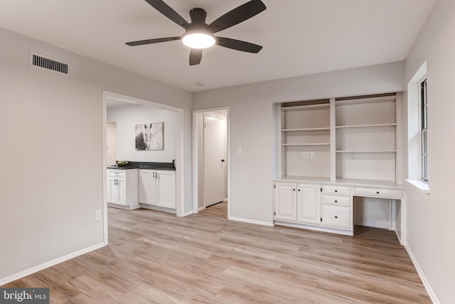 interior space with light wood-style floors, visible vents, ceiling fan, and baseboards