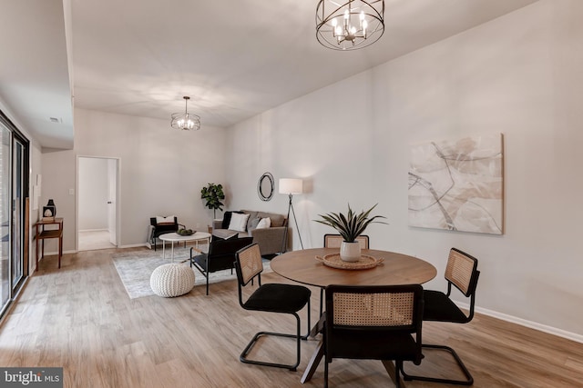 dining space with baseboards, wood finished floors, and a notable chandelier