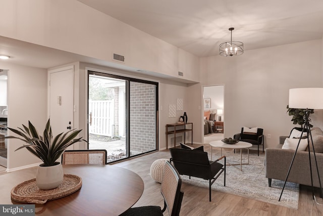 dining room featuring baseboards, a high ceiling, light wood-type flooring, and a notable chandelier