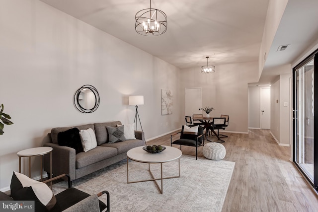 living room featuring an inviting chandelier, baseboards, visible vents, and wood finished floors