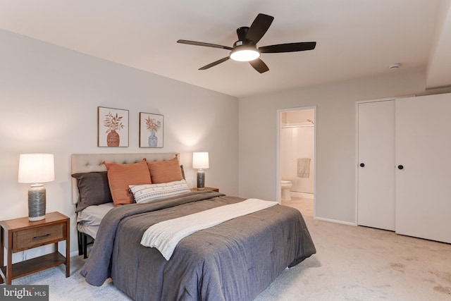 bedroom with baseboards, a ceiling fan, light colored carpet, ensuite bathroom, and a closet