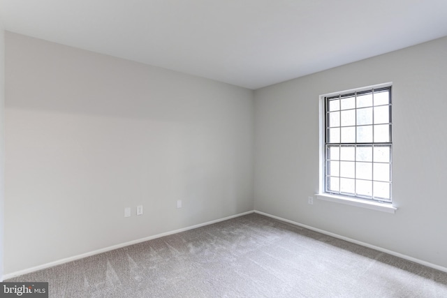 unfurnished room featuring carpet and baseboards