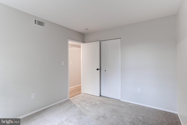 unfurnished bedroom with a closet, carpet flooring, visible vents, and baseboards