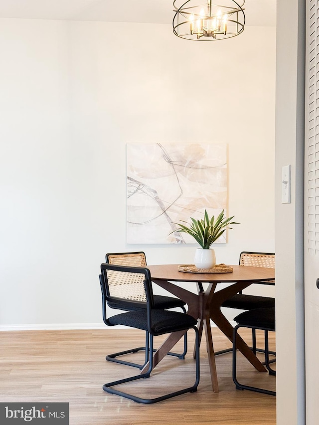 dining space featuring baseboards, wood finished floors, and an inviting chandelier