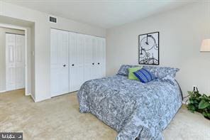 carpeted bedroom featuring a closet and visible vents