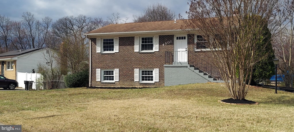 view of front of property with fence, a front lawn, and brick siding