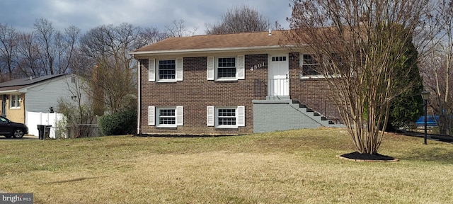 view of front of home with a front lawn, fence, and brick siding