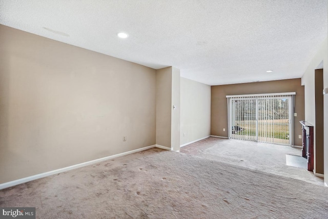 interior space with a textured ceiling, carpet, and baseboards