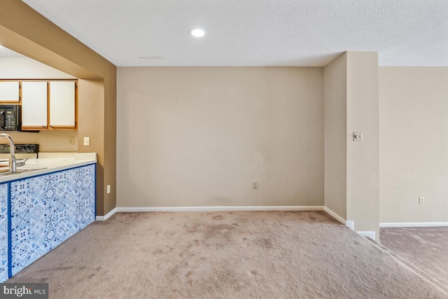 kitchen featuring carpet, black microwave, a textured ceiling, and baseboards