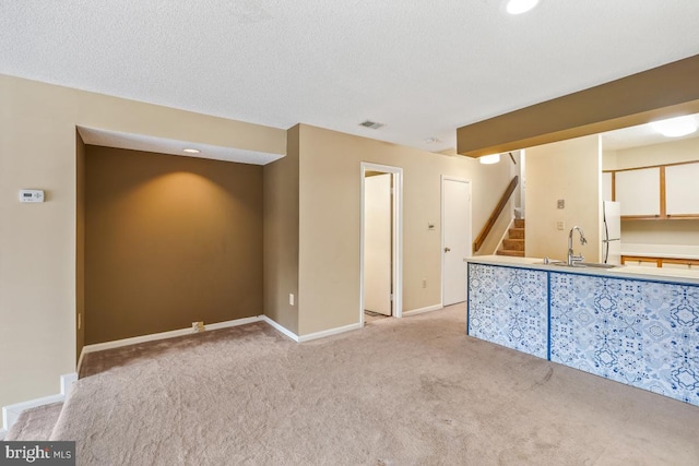 unfurnished room with visible vents, light colored carpet, stairway, a textured ceiling, and a sink