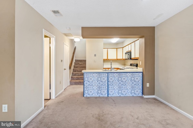 kitchen with light carpet, visible vents, stove, black microwave, and a sink