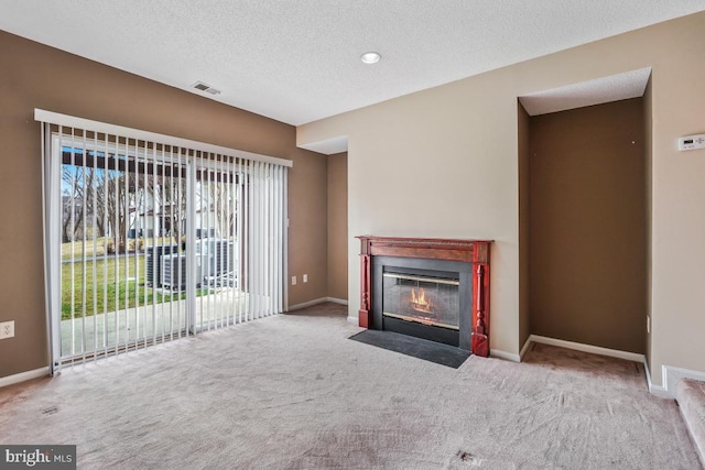 unfurnished living room featuring a fireplace with flush hearth, visible vents, a textured ceiling, and baseboards