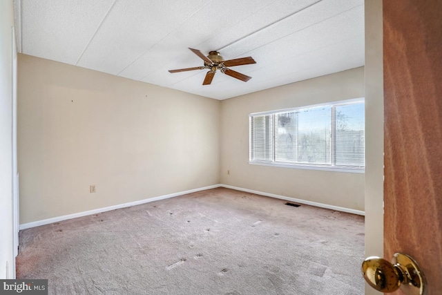 carpeted empty room featuring a ceiling fan, visible vents, and baseboards