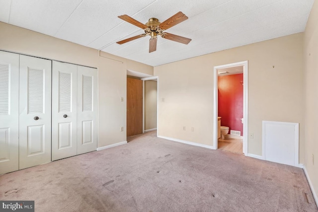 unfurnished bedroom featuring carpet, a closet, baseboards, and ensuite bathroom