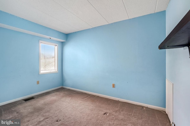 empty room with baseboards, visible vents, and carpet flooring