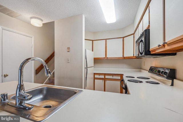 kitchen featuring black microwave, range with electric stovetop, a sink, visible vents, and freestanding refrigerator