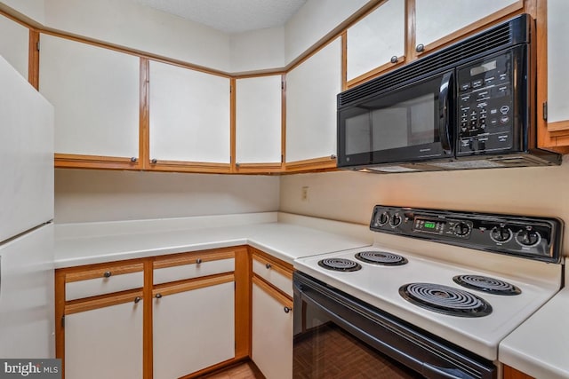 kitchen featuring black microwave, electric stove, light countertops, and freestanding refrigerator