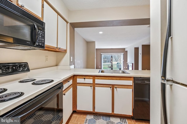 kitchen featuring light countertops, a textured ceiling, black appliances, white cabinetry, and a sink