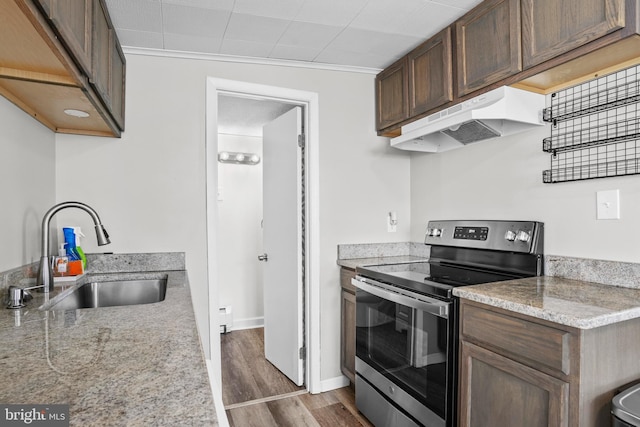 kitchen with dark wood-style floors, under cabinet range hood, a sink, and electric range