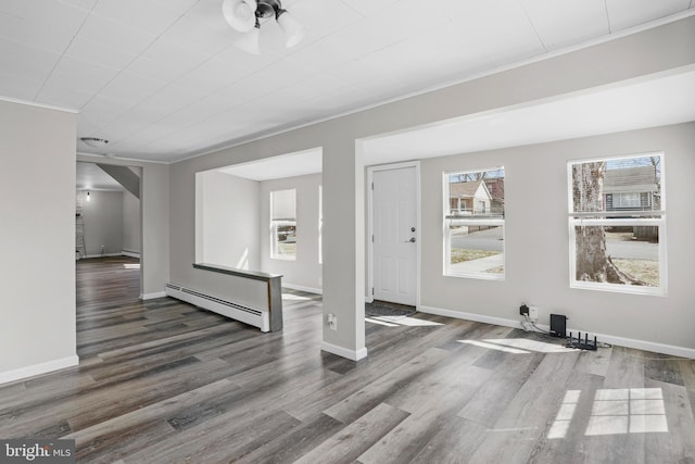 foyer with a baseboard radiator, crown molding, baseboards, and wood finished floors