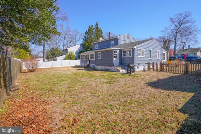 back of property with a fenced backyard, a lawn, and a chimney