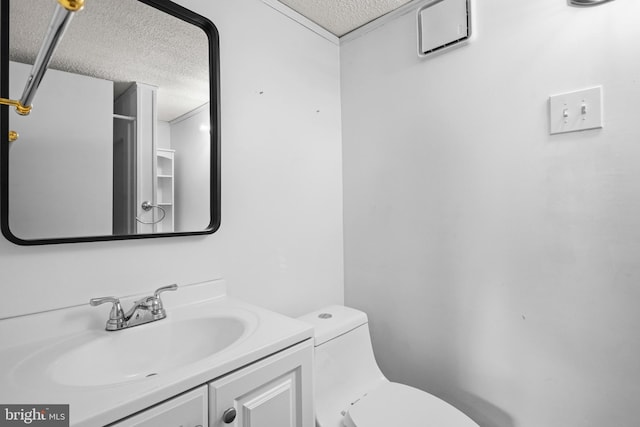 bathroom featuring a textured ceiling, toilet, and vanity